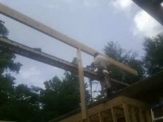 Carpenter setting a ridge beam over a new addition frame — Ice Dam Removal by Roofing Brothers in Davey
