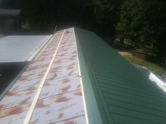 Old rusted panels beside newly installed green metal roofing — Wind Damage Roof Repair by Roofing Brothers in Davey