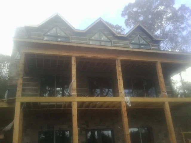Dormers and porch framing on a large log home under construction — Roof Coating work by our crew in Davey