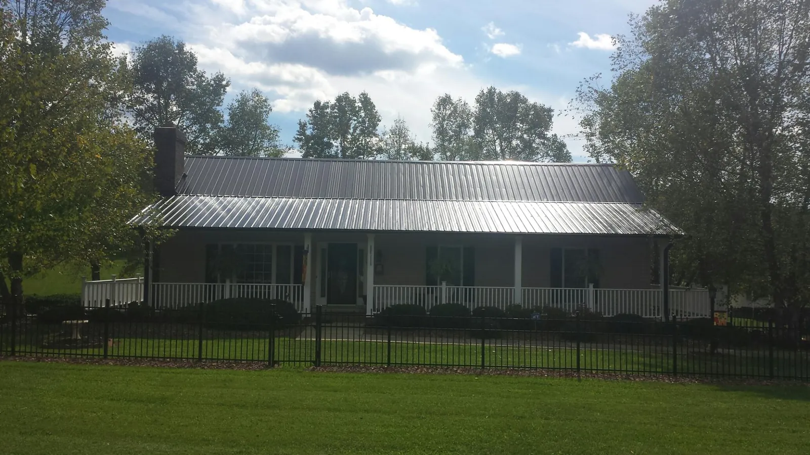 Gray metal roof on a brick ranch with a full width front porch — Gutter Guard Installation work by our crew in Davey